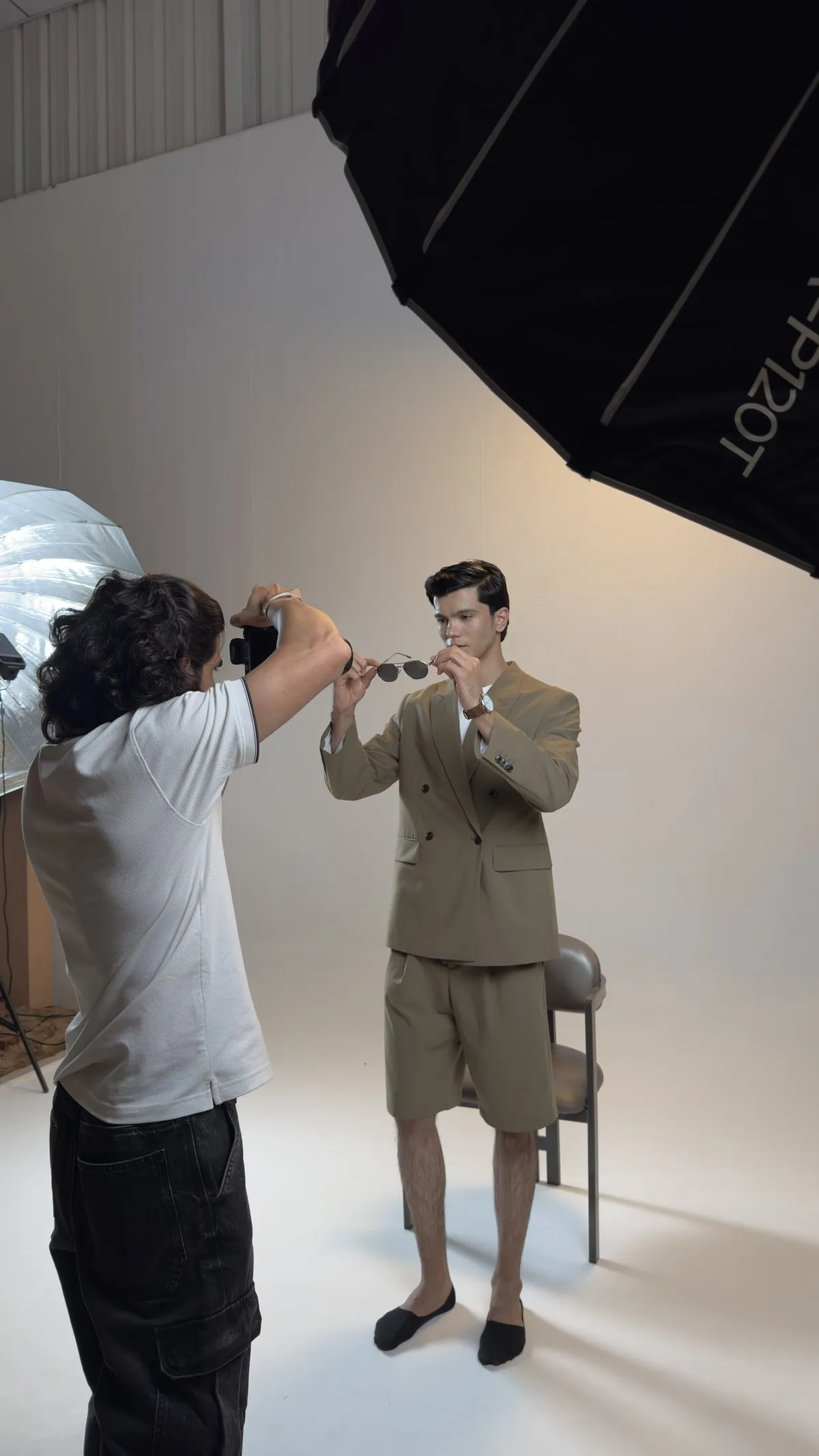 Behind the scenes: a photographer shooting a model in a beige suit on the studio set