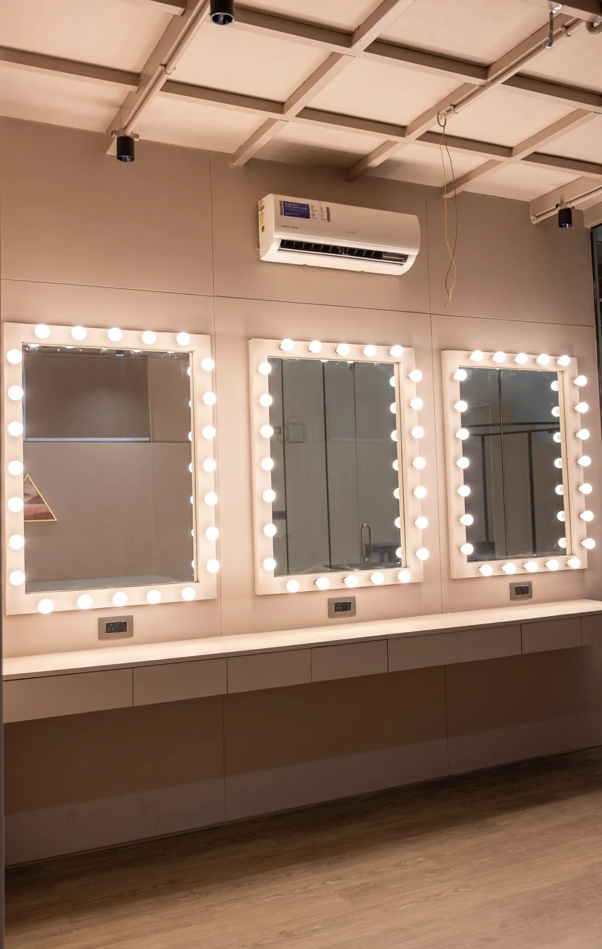 Make-up room with three bulb-lit vanity mirrors